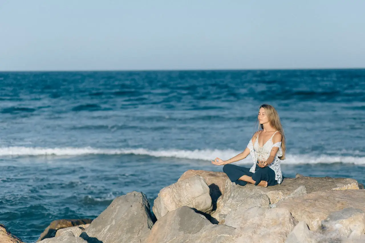 Woman meditating on a seawall of rocks overlooking the ocean