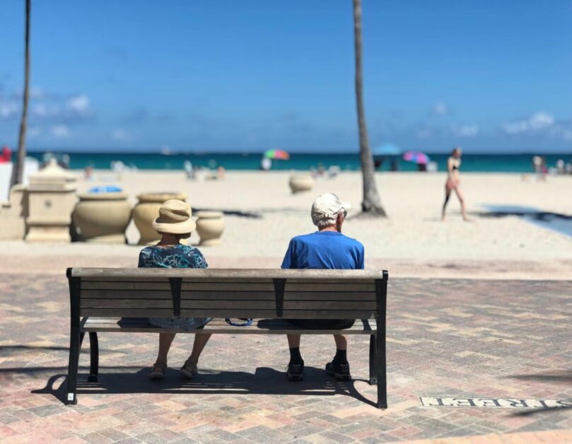 Couple sitting on a bench in front of the beach during retirement